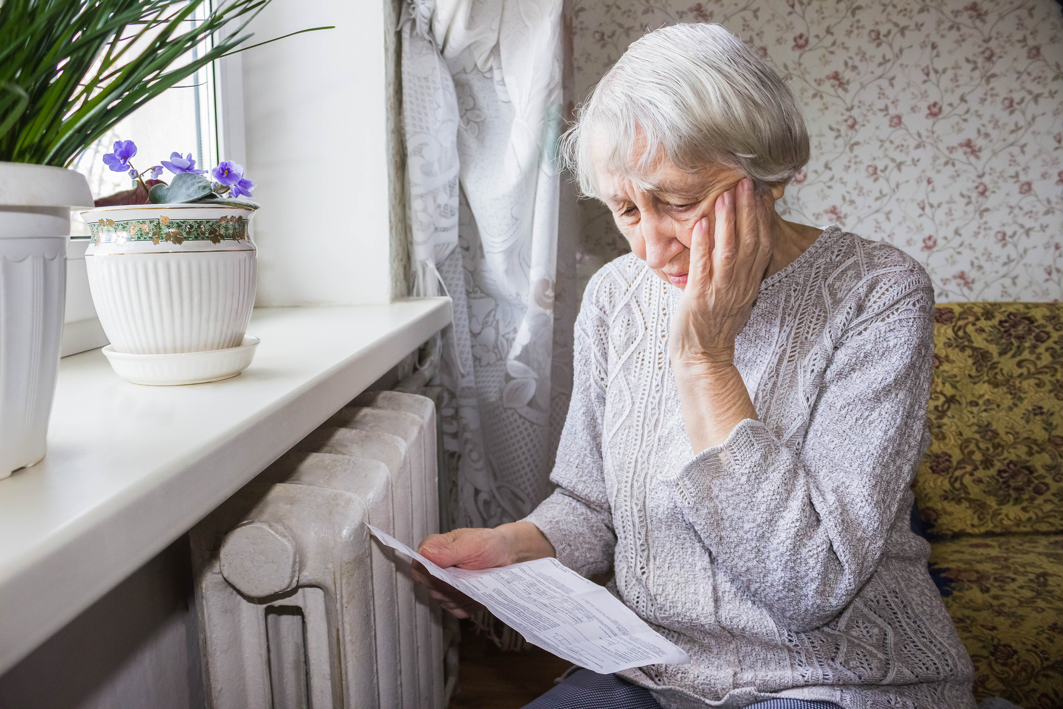 Vrouw met energiefactuur in de hand voor de verwarming.