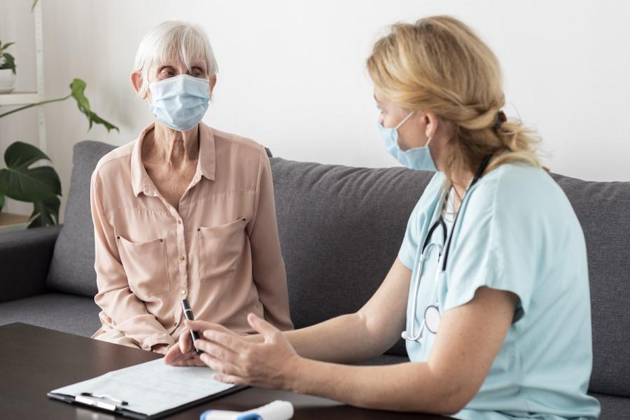 Verpleegster praat met ouder dame