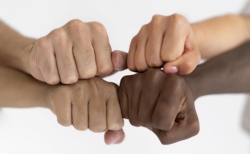 4 handen met een verschillende huidskleur geven elkaar een vuistje