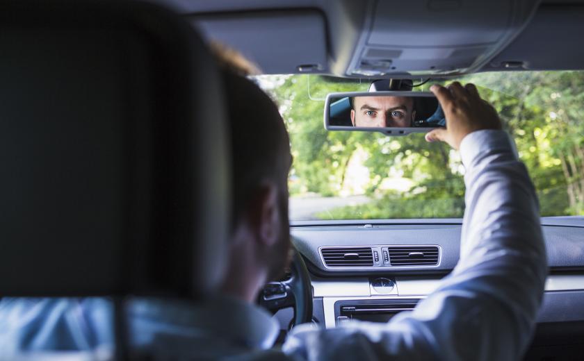 man zit in de wagen en zet spiegel goed